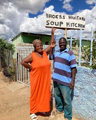 Annette and her husband in front of the soup kitchen sign